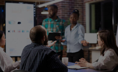 Professionals collaborating in a boardroom as colleagues present strategy to the team