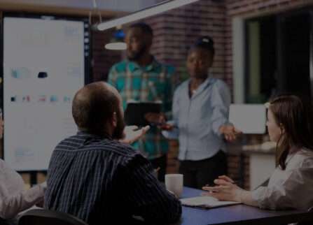 Professionals collaborating in a boardroom as colleagues present strategy to the team